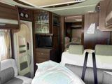 two beds in the back of a camper with a flat screen tv