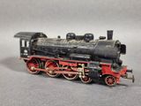 un train miniature noir et rouge posé sur une surface grise