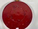 a red clock on a white surface with a gold bell