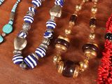 many different necklaces and bracelets on a wooden table