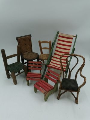 cinq chaises miniatures et une chaise posées sur une surface blanche