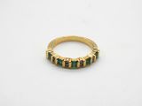 a close up of a gold ring with green and black stones