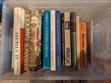de nombreux livres dans une boîte en plastique posée par terre