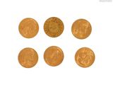 six pièces d'or sont disposées en ligne sur une surface blanche