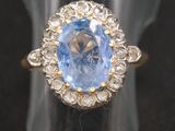 gros plan d'une bague avec une pierre bleue entourée de diamants blancs