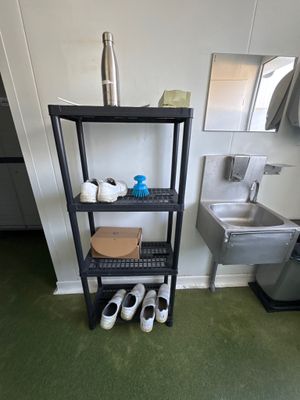une étagère noire sur laquelle sont posées des chaussures, dans une petite pièce