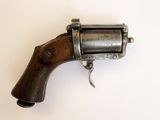 un vieux pistolet avec une poignée en bois sur une surface blanche