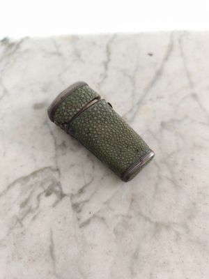 un petit briquet vert posé sur une surface en marbre