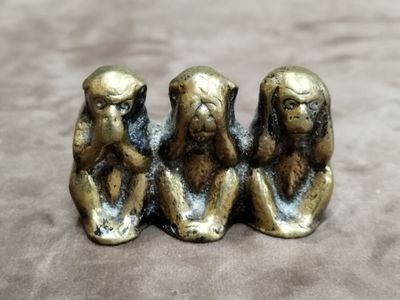 trois singes sages assis sur une table, la main posée sur le menton