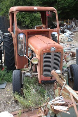 an old rusted orange truck parked in a junkyard