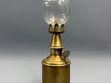 une lampe à huile ancienne en laiton, surmontée d'un globe en verre