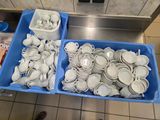 deux bacs posés par terre, contenant des assiettes et des bols