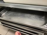 a person holding a tray of food in front of an oven