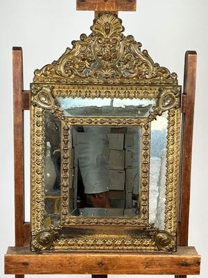 a mirror on a stand with a vase on top of it