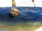 a blue bowl with a gold handle hanging from a chain