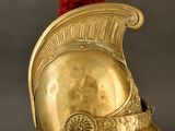 an antique gold helmet with a red pom pom on top of it