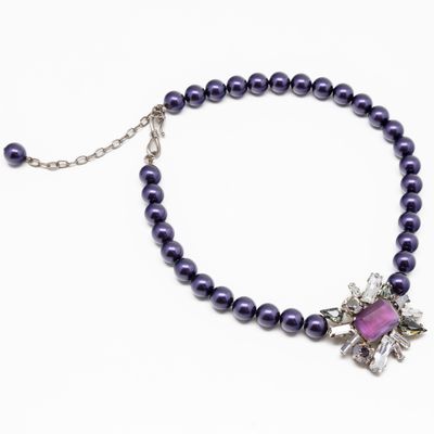 un gros plan sur un collier orné de perles violettes et d'une fleur