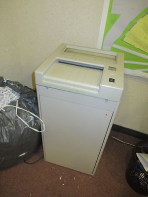 une déchiqueteuse à papier blanche posée à côté d'une poubelle
