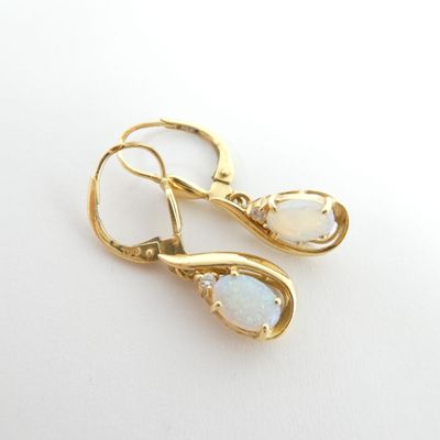 une paire de boucles d'oreilles en oplite et diamants posées sur un fond blanc