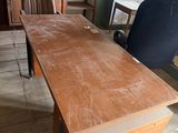 a large wooden table with a black chair in the corner