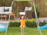 a young girl swinging on a swing set in the yard