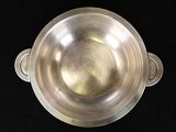 a silver bowl on a black surface with a black background