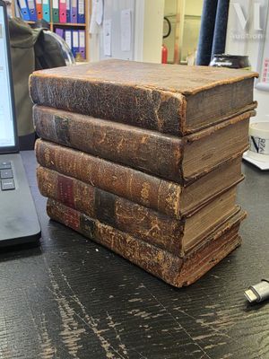 books stacked on top of each other on a desk with a laptop in the background