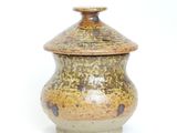 a small ceramic jar with a lid on a white background