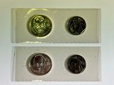 three different coins are in a clear box on a white surface