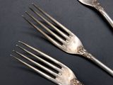 three forks and a spoon on a black surface
