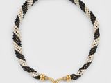 un collier en perles noires et blanches orné d'une breloque en forme de perle
