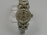 a silver watch with diamonds on it sitting on a white surface