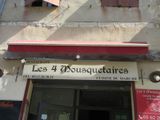 une enseigne indiquant « Les 4 mousquetaires » sur la façade d'un immeuble