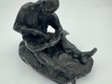 statue représentant un homme assis sur un rocher avec un chien