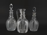 three clear glass decanters on a black surface with a black background