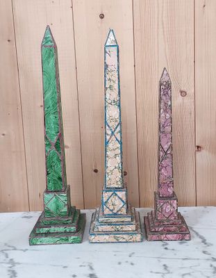 trois obélisques en pierre de couleurs différentes posés sur une table