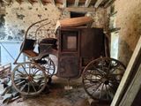 une voiture tirée par des chevaux, assise dans une pièce avec un mur en pierre
