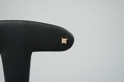 un gros plan sur une paire de boucles d'oreilles en or posées sur une chaise noire