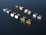 four pairs of gold and silver cufflinks sitting on top of a black surface