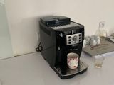 une cafetière posée sur un plan de travail, avec une tasse dessus