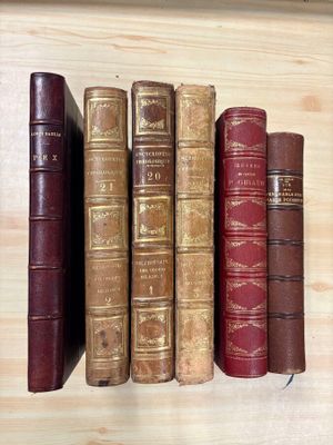 several old books are lined up on a shelf on a table