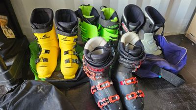 many pairs of ski boots lined up on the floor