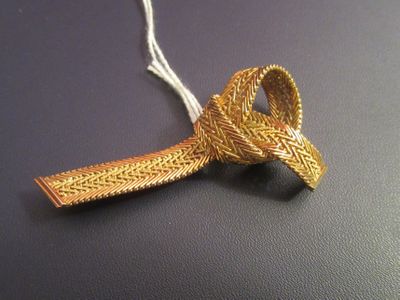 a gold tie with a knot on it on a black surface