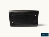 a black leather purse sitting on top of a white surface