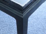 a black coffee table with a glass top on a carpeted floor