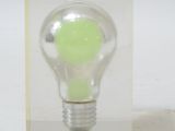 a green light bulb in a clear box on a white surface
