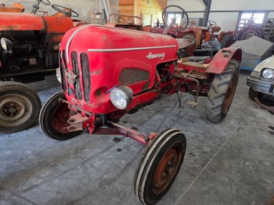 a red tractor parked in a garage with other tractors