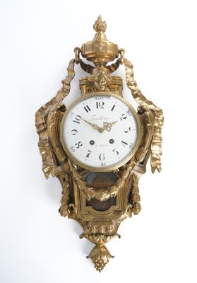 a gold clock hanging on the wall on a white wall