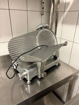 a meat slicer sitting on top of a table in a kitchen