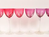 six wine glasses are lined up in a row on a white surface